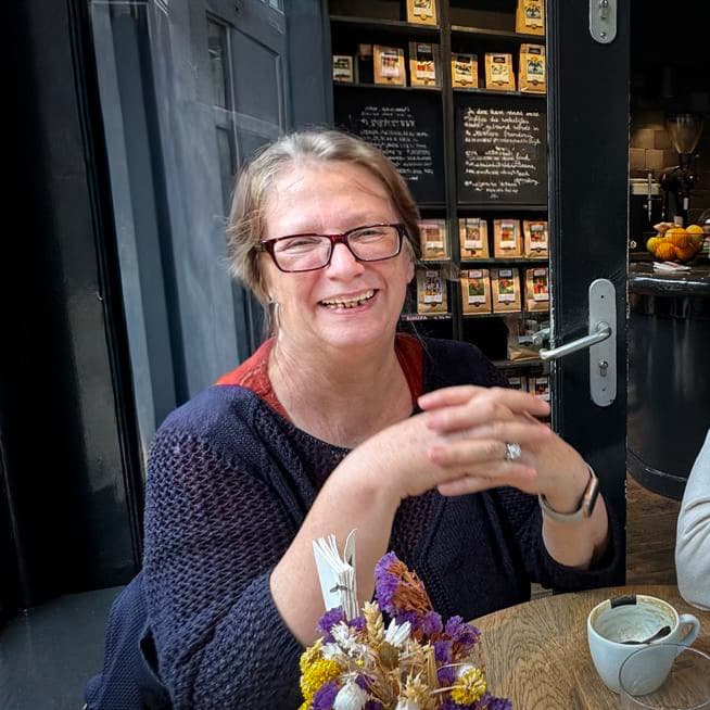 Franziska Roch sitzt lächelnd bei einer Tasse Kaffee